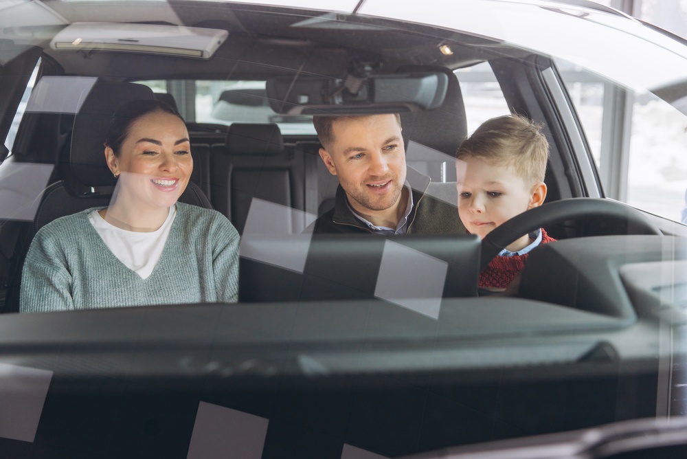 Happy,Family,Of,Three,Sitting,Inside,New,Automobile,,Evaluating,Features